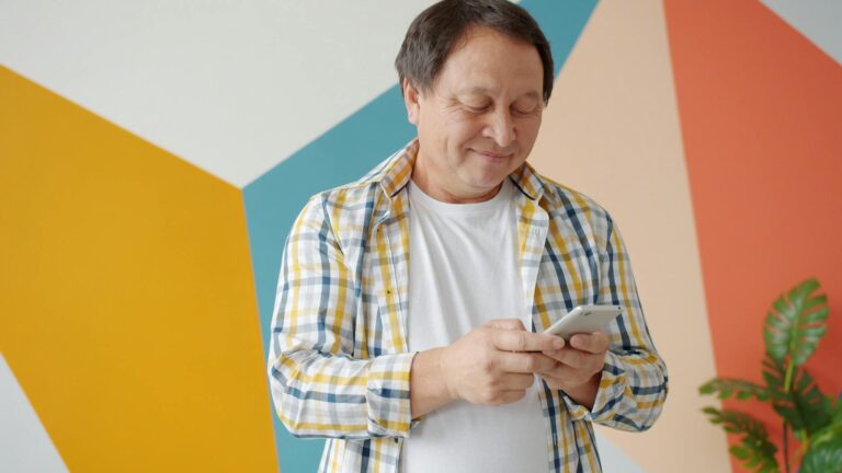 homme regardant son téléphone avec sourire, cœur rouge à l'écran