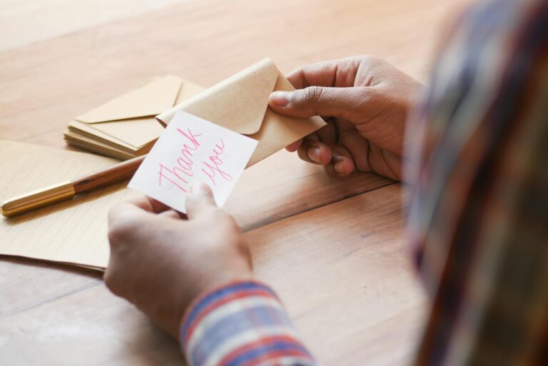 Femme souriante écrivant un petit mot gentil sur une carte colorée