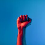 Main levée avec poing fermé sur fond jaune lumineux, symbole de courage et détermination
