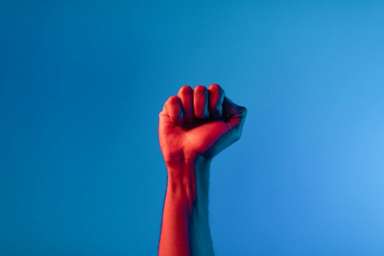 Main levée avec poing fermé sur fond jaune lumineux, symbole de courage et détermination