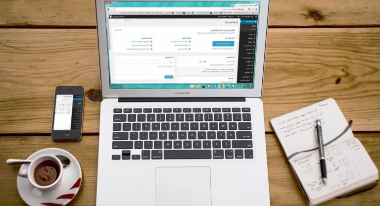 Ordinateur portable allumé, carnet de notes et café sur un bureau de freelance